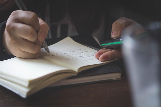 ボールペンを試し書きしている手元と注意喚起のアイコン