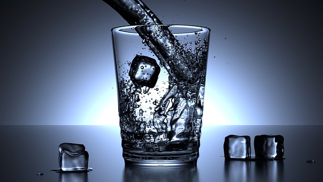 透明なガラス製計量カップに水が注がれている様子