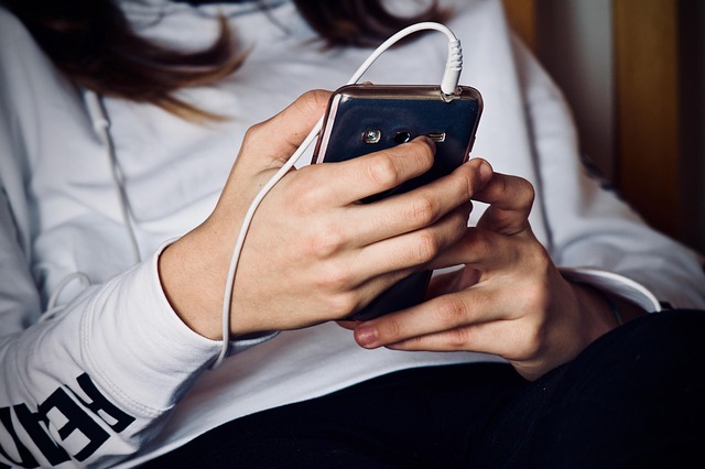 体重計に乗ってスマホアプリでデータを確認している女性のイメージ