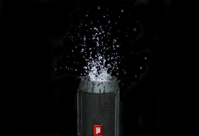 様々なポータブルスピーカーが並べられ、音楽を楽しむ人々が背景にいるイメージ